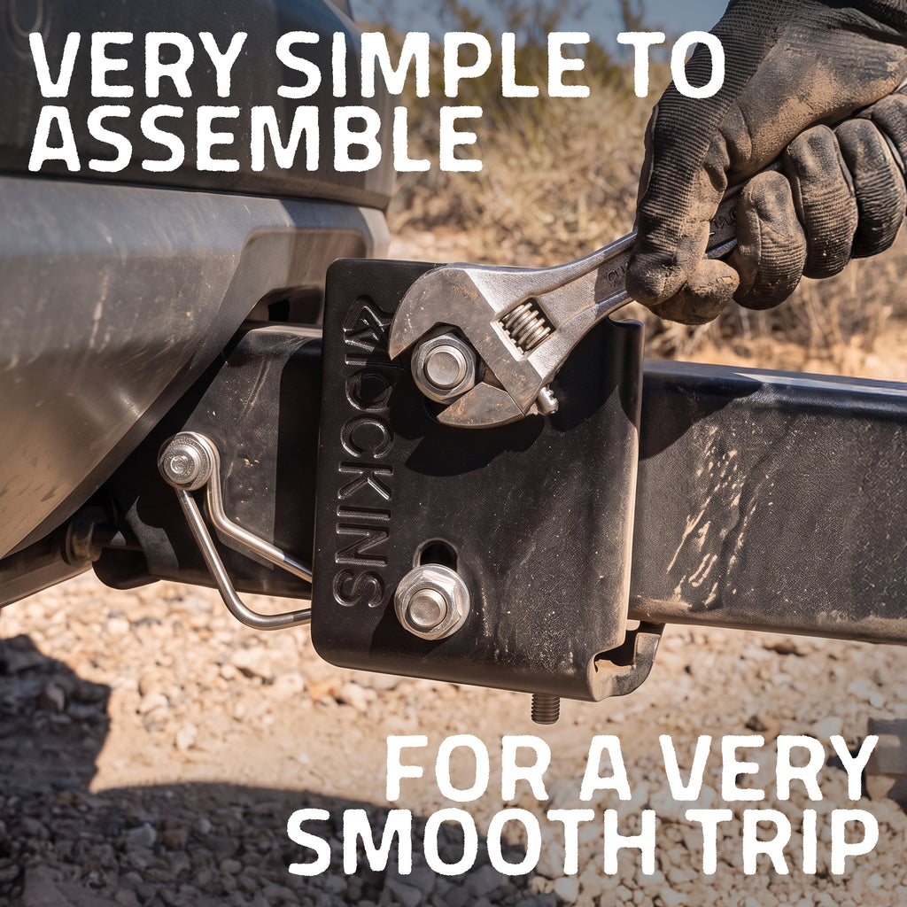 A gloved hand uses an adjustable wrench to tighten a bolt on a black hitch receiver labeled 'SMOOKINS'. Large white text reads 'VERY SIMPLE TO ASSEMBLE' at the top and 'FOR A VERY SMOOTH TRIP' at the bottom, with an outdoor gravel background.