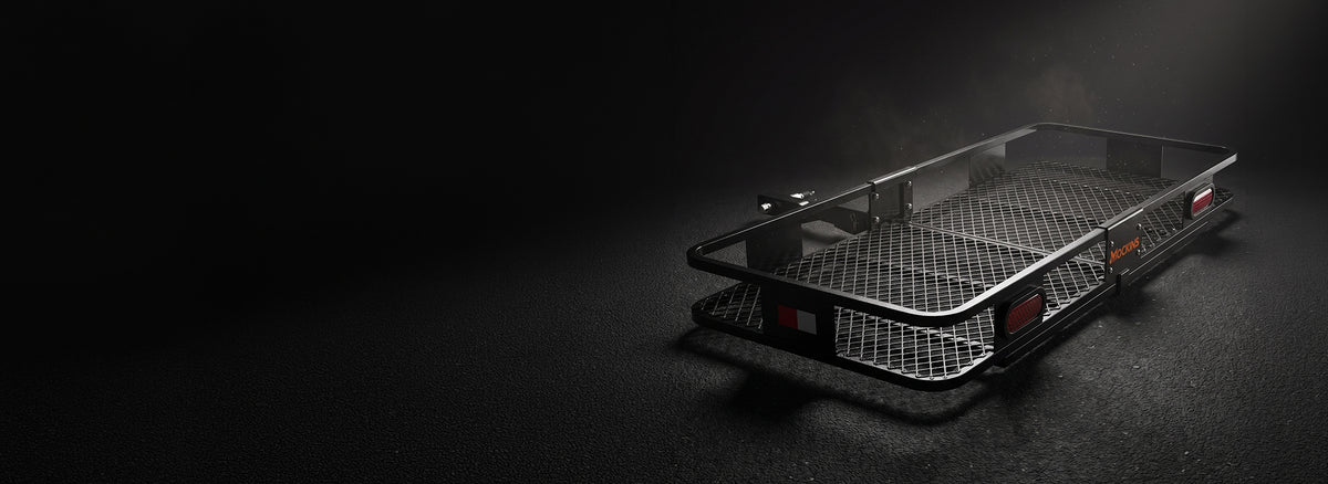 A black metal mesh cargo bed or trailer rack with side rails, photographed on a dark studio background with dramatic side lighting.