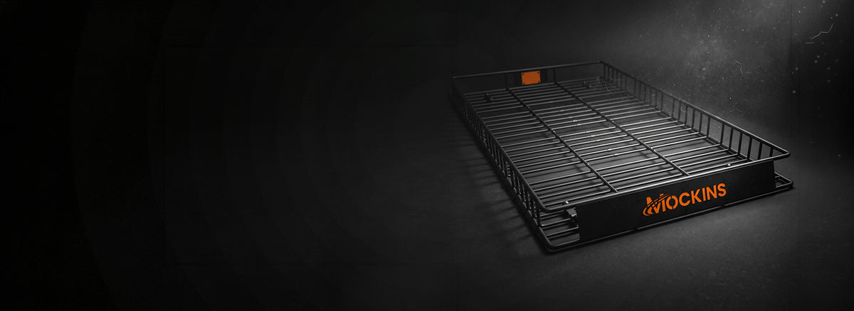 A black metal wire rack tray with orange MOCKINS branding on the front, photographed on a dark studio background with dramatic lighting.